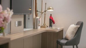 Una camera moderna con una scrivania, una sedia, una lampada, uno specchio e un vaso con fiori.