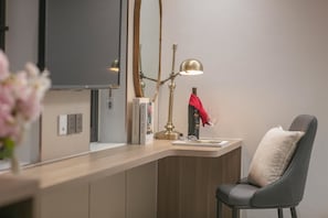 A modern room with a desk, a chair, a lamp, a mirror, and a vase with flowers. - Amira Hotel Ngoc Han Bac Ninh (Bac Ninh)