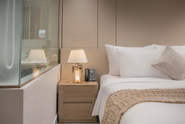 A hotel room with a bed, bedside lamp, nightstand, and a mirror reflecting the room. - Amira Hotel Ngoc Han Bac Ninh (Vo Cuong)