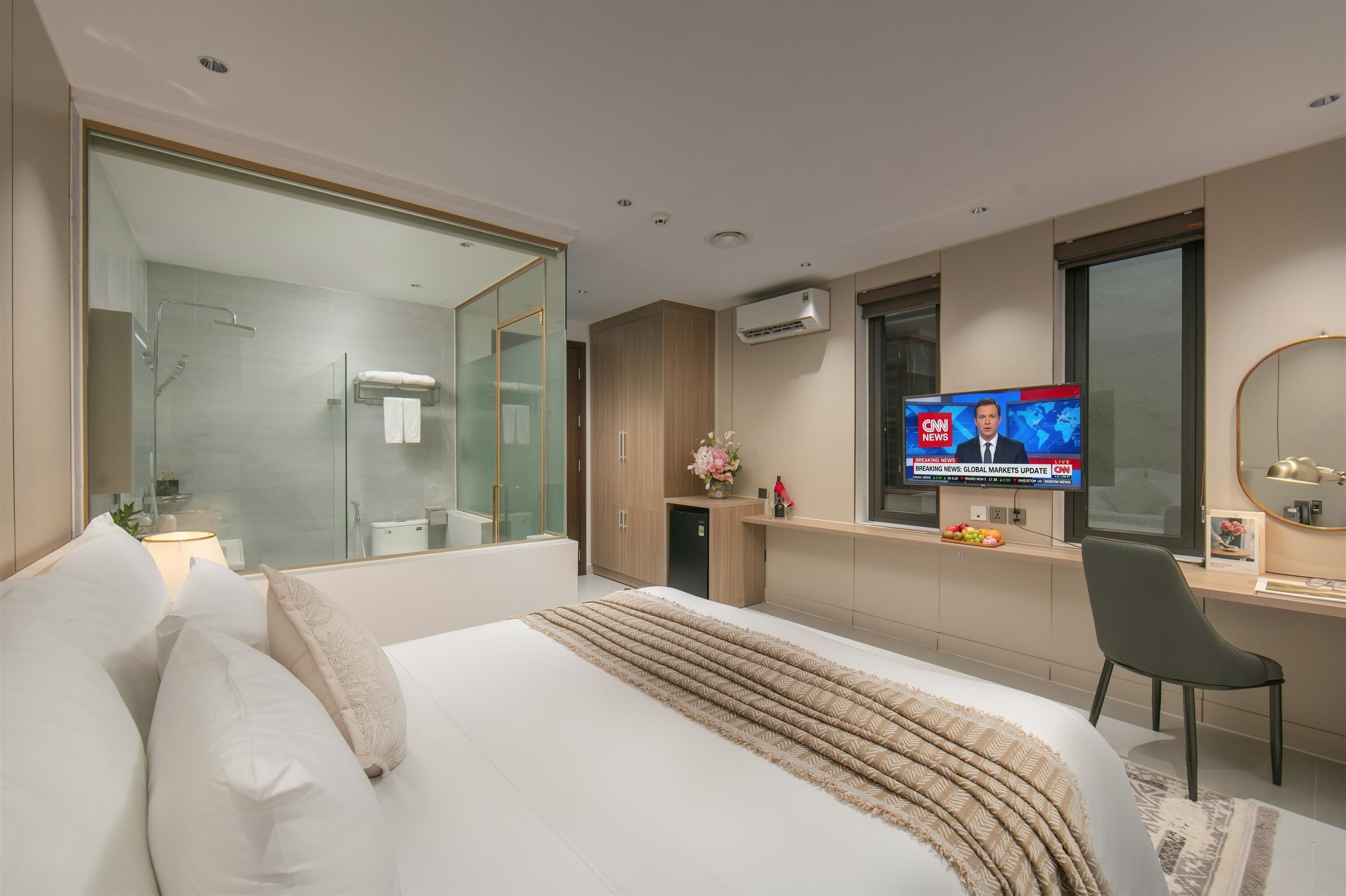Una habitación de hotel moderna con una cama, un televisor mostrando CNN, un escritorio y un espejo grande.