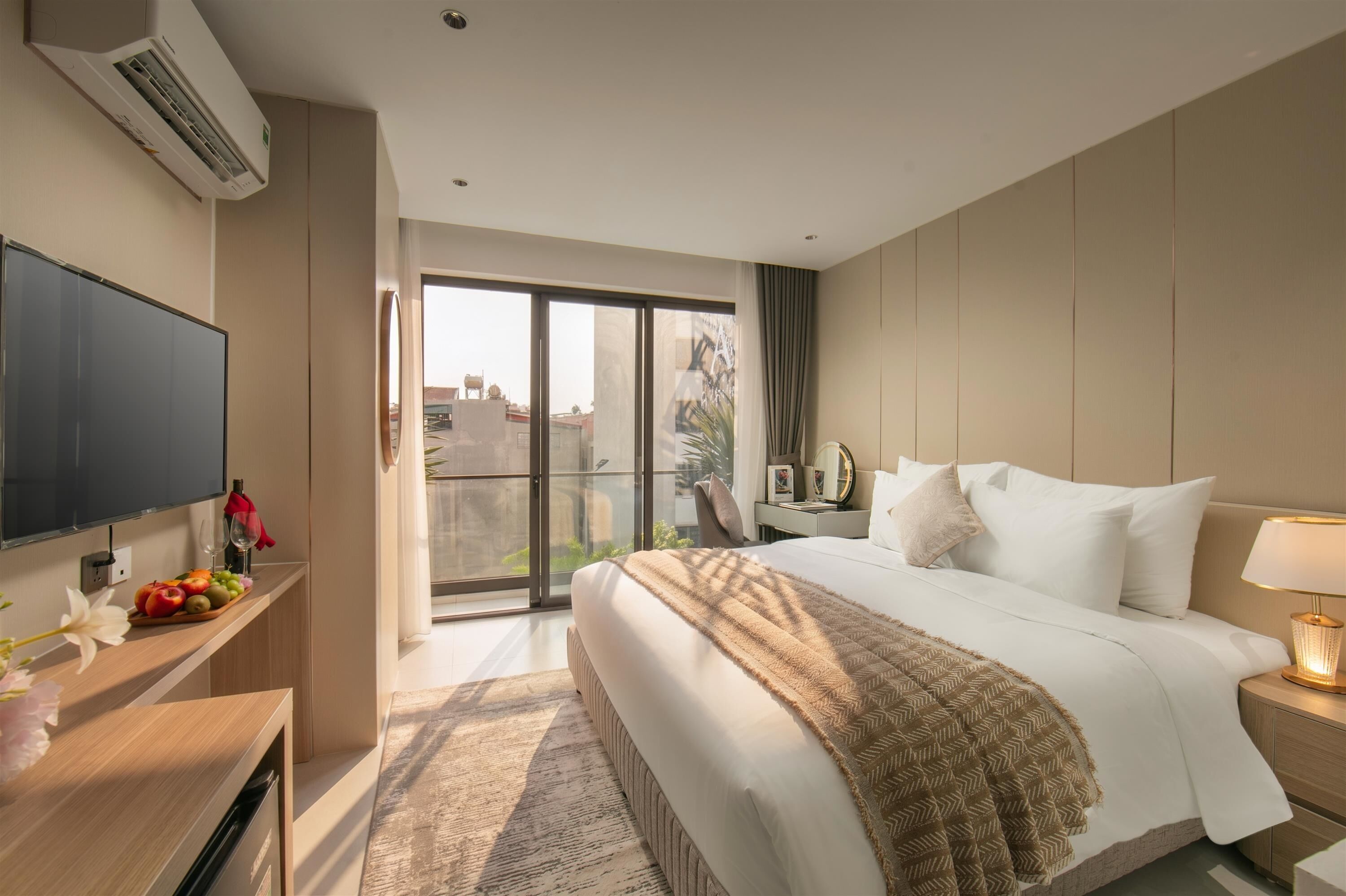 A hotel room with a bed, bedside table, TV, and a balcony with a view.