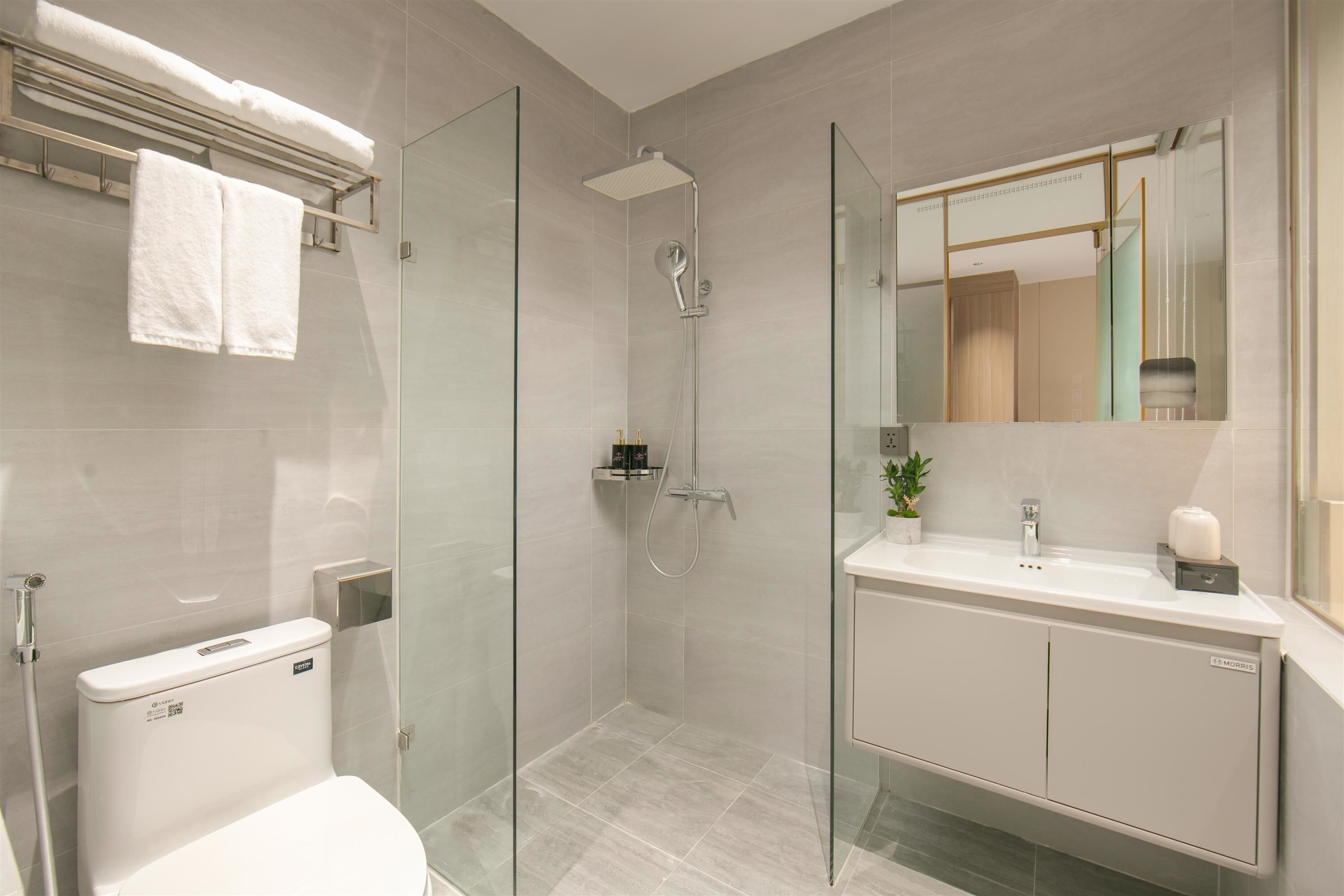 Une salle de bain moderne avec une douche à parois de verre, des toilettes blanches et un meuble-lavabo avec un miroir.
