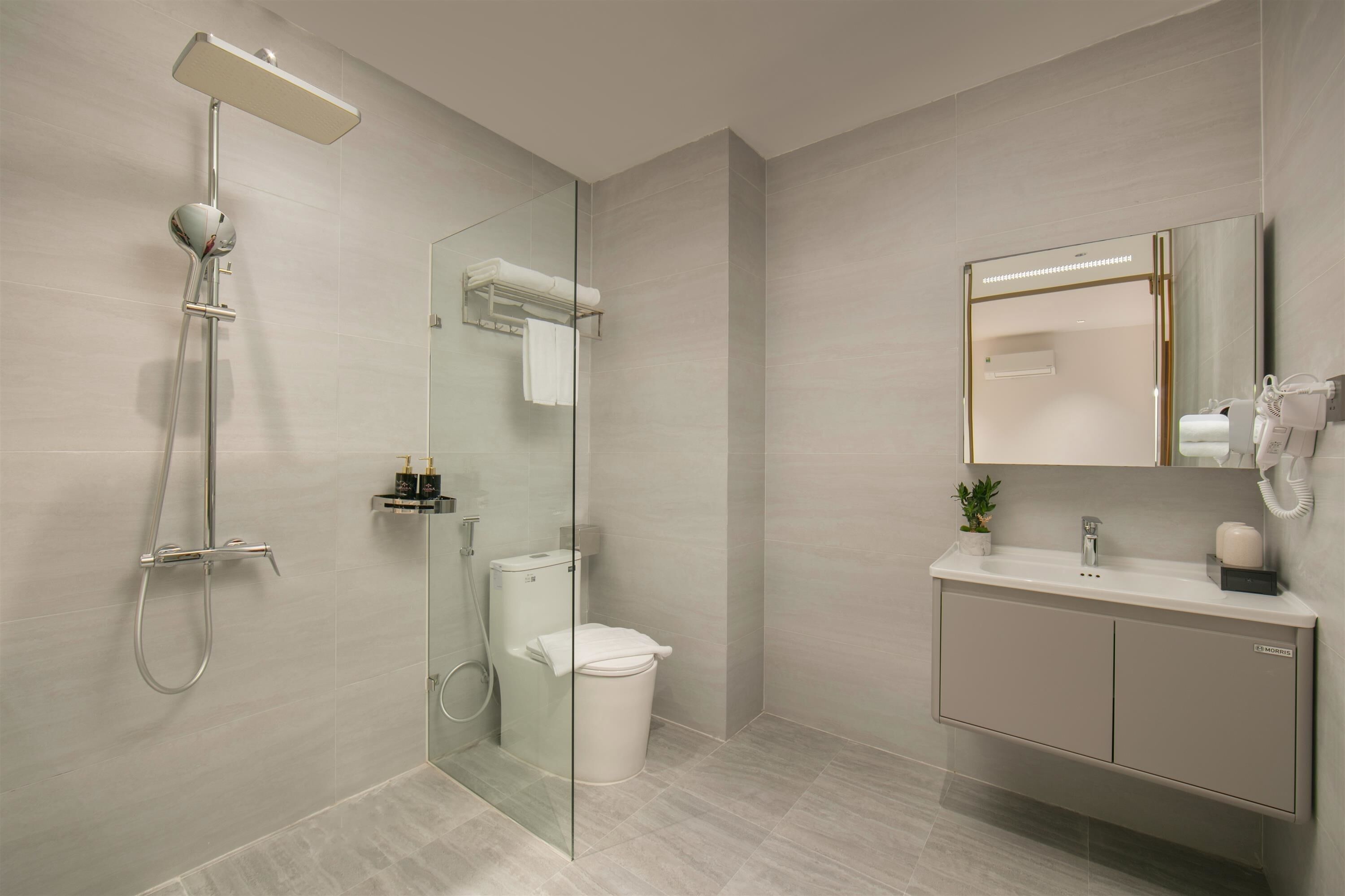 Un baño moderno con ducha acristalada, inodoro, lavabo con espejo y armario.