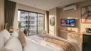 Camera d'albergo con un letto grande, una televisione che mostra CNN, un balcone con vista sugli edifici e un condizionatore d'aria.