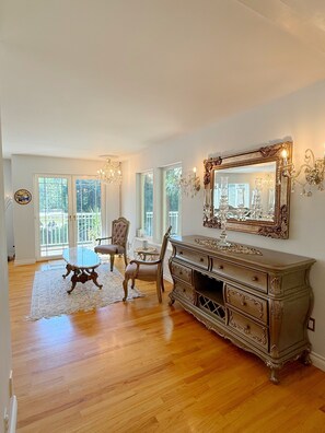 A spacious room with hardwood flooring, a large ornate dresser, a glass table, and a chair. -  5 bedroom, 4 Bathroom home in West Vancouver perfect for FIFA & large groups. (West Vancouver)