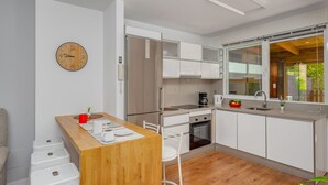 A modern kitchen with white cabinets, a wooden countertop, a built-in oven, and a window with a view of greenery. - Moon Beach Garden View (Mijas)