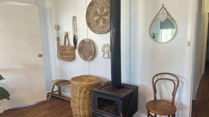 A room with a wood-burning stove, wicker baskets, a chair, and decorative wall hangings. - The Nest, Wifi - NO Pets (Robe)