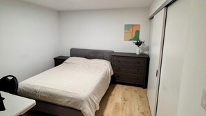 Ein Schlafzimmer mit Bett, Nachttisch, Stuhl und kleinem Schreibtisch.