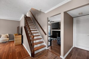 A staircase leading to a second floor, a living room with a fireplace, and a closed door.