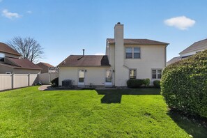 A two-story house with a chimney, a front yard, and a small garden area.