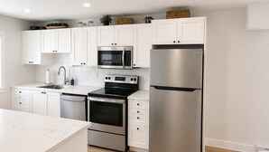 Cocina moderna con armarios blancos, electrodomésticos de acero inoxidable y encimera de mármol.
