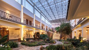 Ein mehrgeschossiges Atrium mit Glasdecke, Holzgalerien und Zimmerpflanzen.