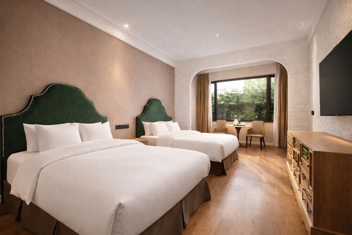 Een hotelkamer met twee bedden, een bureau, een stoel en een televisie.