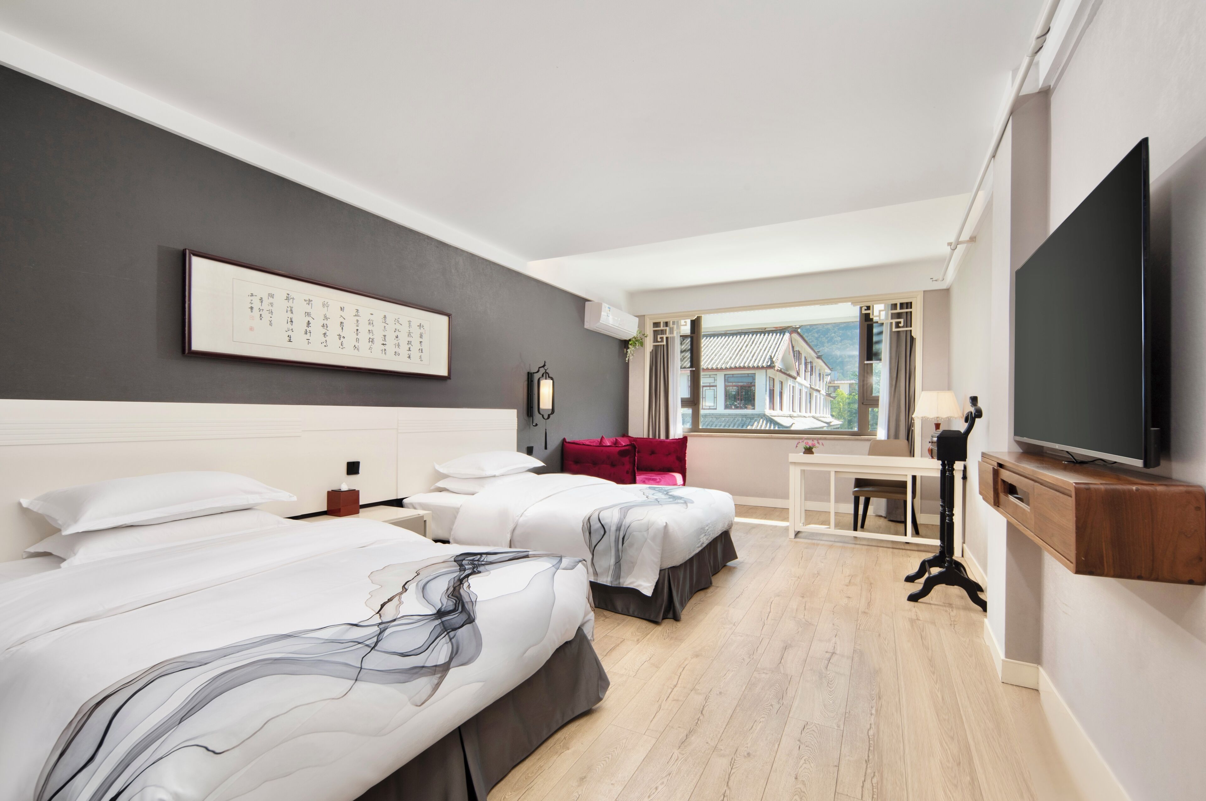 Ett hotellrum med två sängar, ett skrivbord, en TV och ett fönster med utsikt.