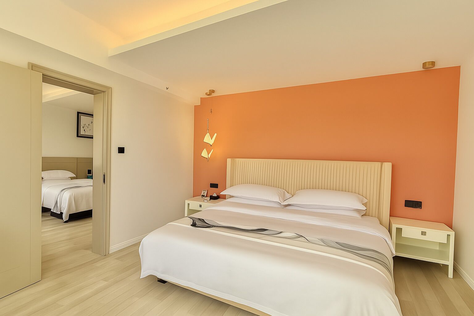 A modern hotel room with a large bed, bedside tables, and a mirror.