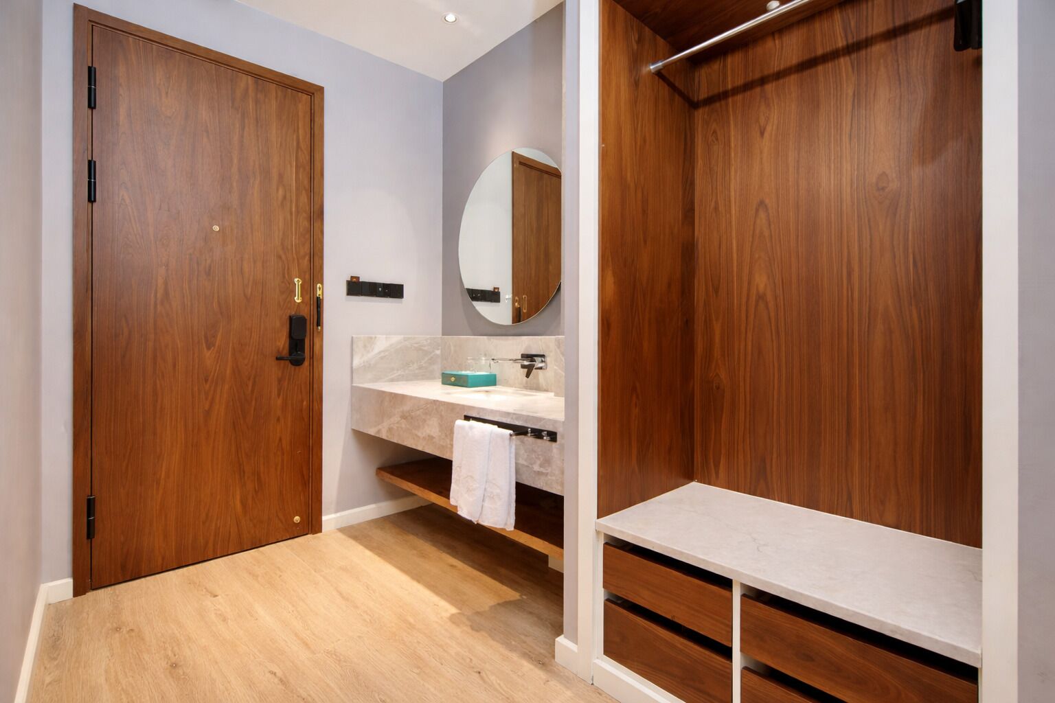 A modern bathroom with wooden doors, a marble countertop, a mirror, and a towel rack.