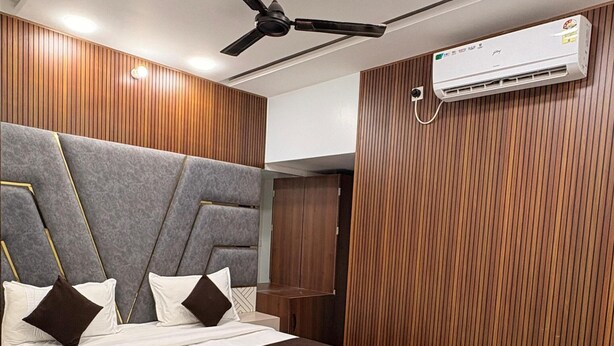 Ein modernes Schlafzimmer mit Bett, Deckenventilator, Klimaanlage und Holzwandverkleidung.