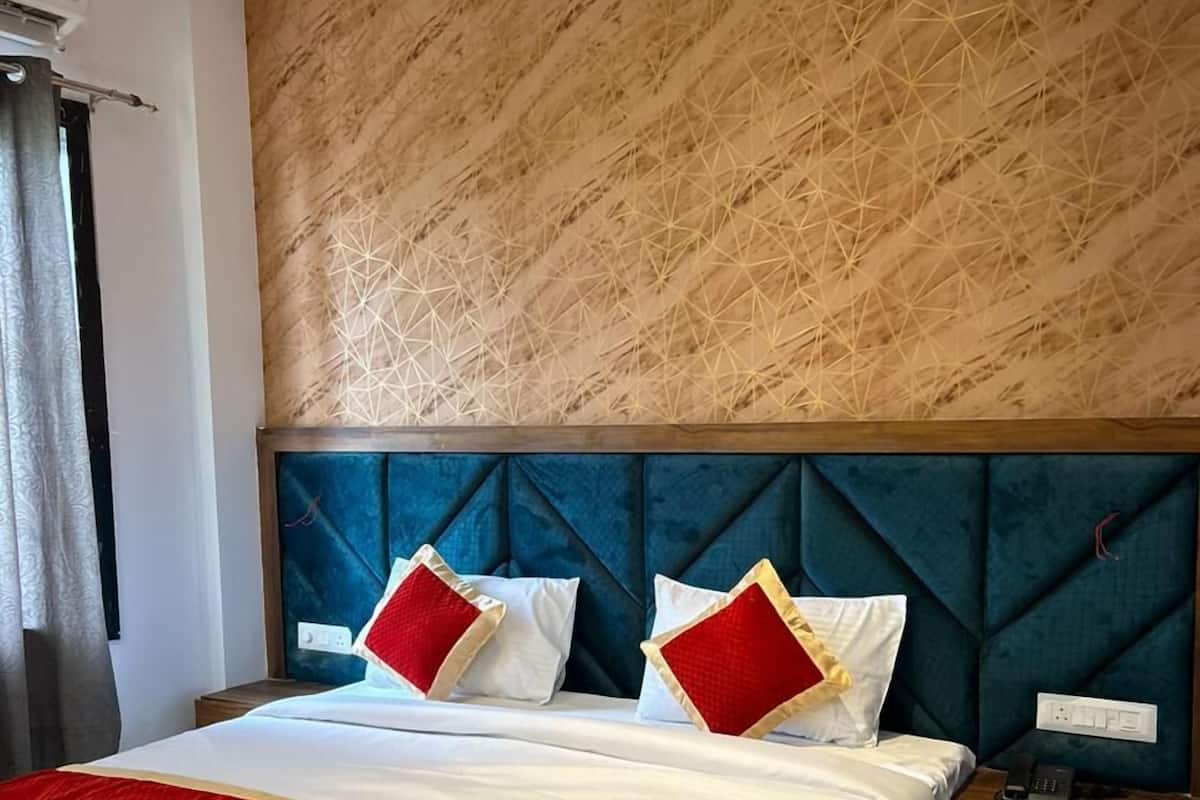 A hotel room with a large bed, a headboard with a geometric pattern, and a bedside telephone.