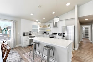 A modern kitchen with a large island, stainless steel appliances, and pendant lighting.