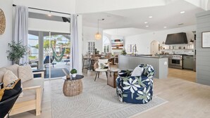 A spacious living area with a dining set, a kitchen with modern appliances, and a view to the outside. - Pearl of Paradise | Waterfront Pool Home w/ Dock in Palm Coast, Game Room, Near Flagler Beach (Palm Coast)