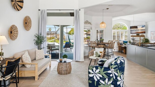 A spacious living area with a sofa, chairs, a dining table, and a kitchen in the background. - Pearl of Paradise | Waterfront Pool Home w/ Dock in Palm Coast, Game Room, Near Flagler Beach (Palm Coast)