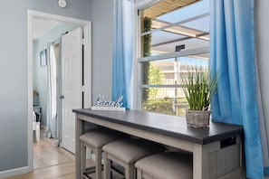 A hallway with a bench, a sign reading "Beach," and a window with blue curtains. - AMI Escape in 10 Min! Pool, Spa, Firepit & Game Room – Pet Friendly (Bradenton)