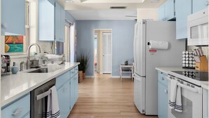 A modern kitchen with light blue cabinets, stainless steel appliances, and a wooden floor. - AMI Escape in 10 Min! Pool, Spa, Firepit & Game Room – Pet Friendly (Bradenton)