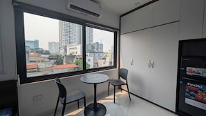 A room with a large window, two chairs, a small table, and a wardrobe. - Aira Khuong Thuong Apartment (Hanoi)