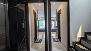 A hallway with a glass door, a staircase, and a view into a room with a bed and a window. - Aira Khuong Thuong Apartment (Hanoi)