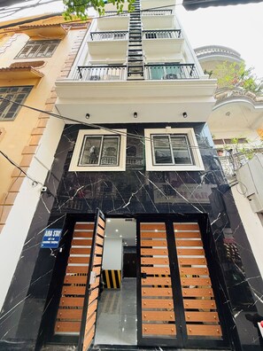 A multi-story building with a black marble facade, wooden shutters, and a sign indicating 'AIRA STAY.' - Aira Khuong Thuong Apartment (Kim Lien)