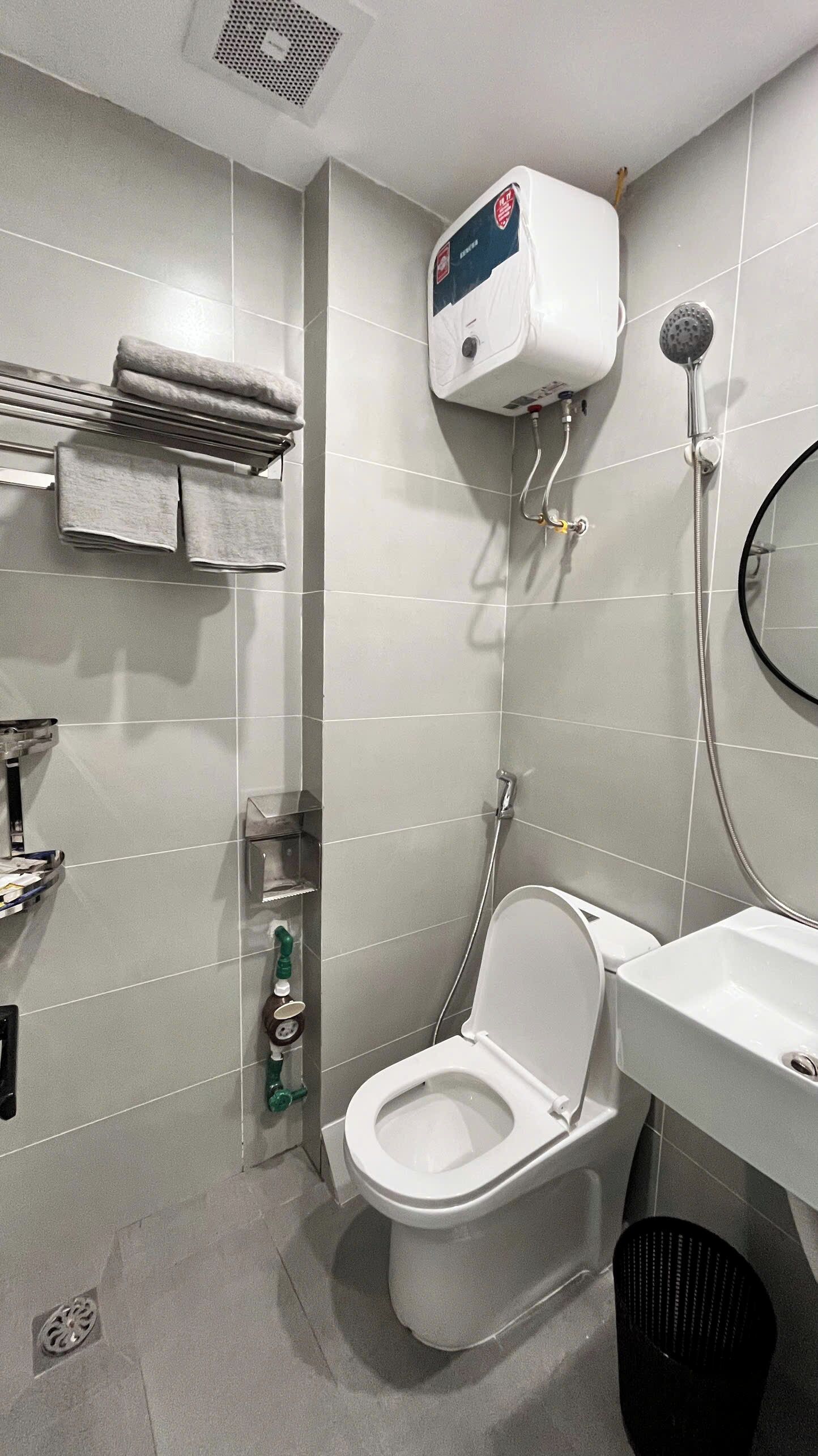 Een badkamer met toilet, douche, wastafel en een handdoekhouder.