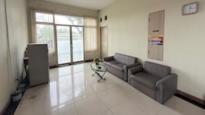 A waiting area with a reception desk, two sofas, a clock, and a sign on the wall. - Guesthouse Anggrek BSD (South Tangerang)