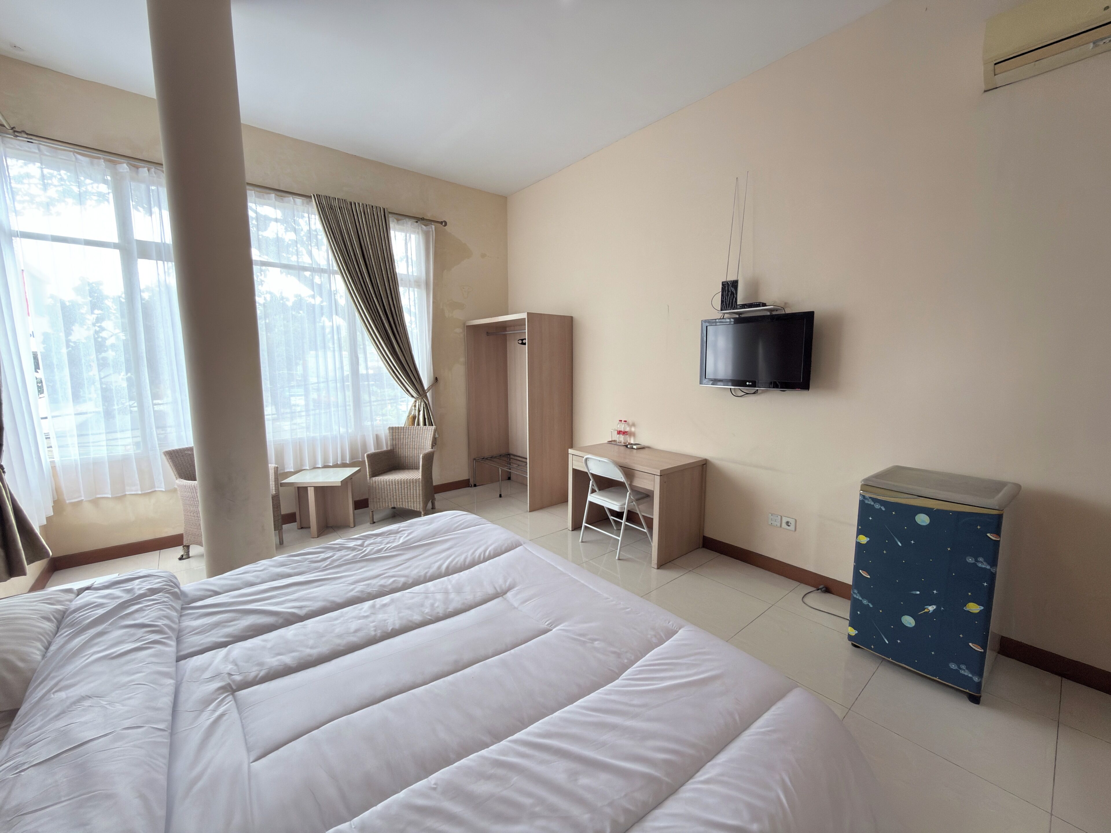 A hotel room with a bed, a desk, a chair, a wardrobe, a television, and a cabinet.