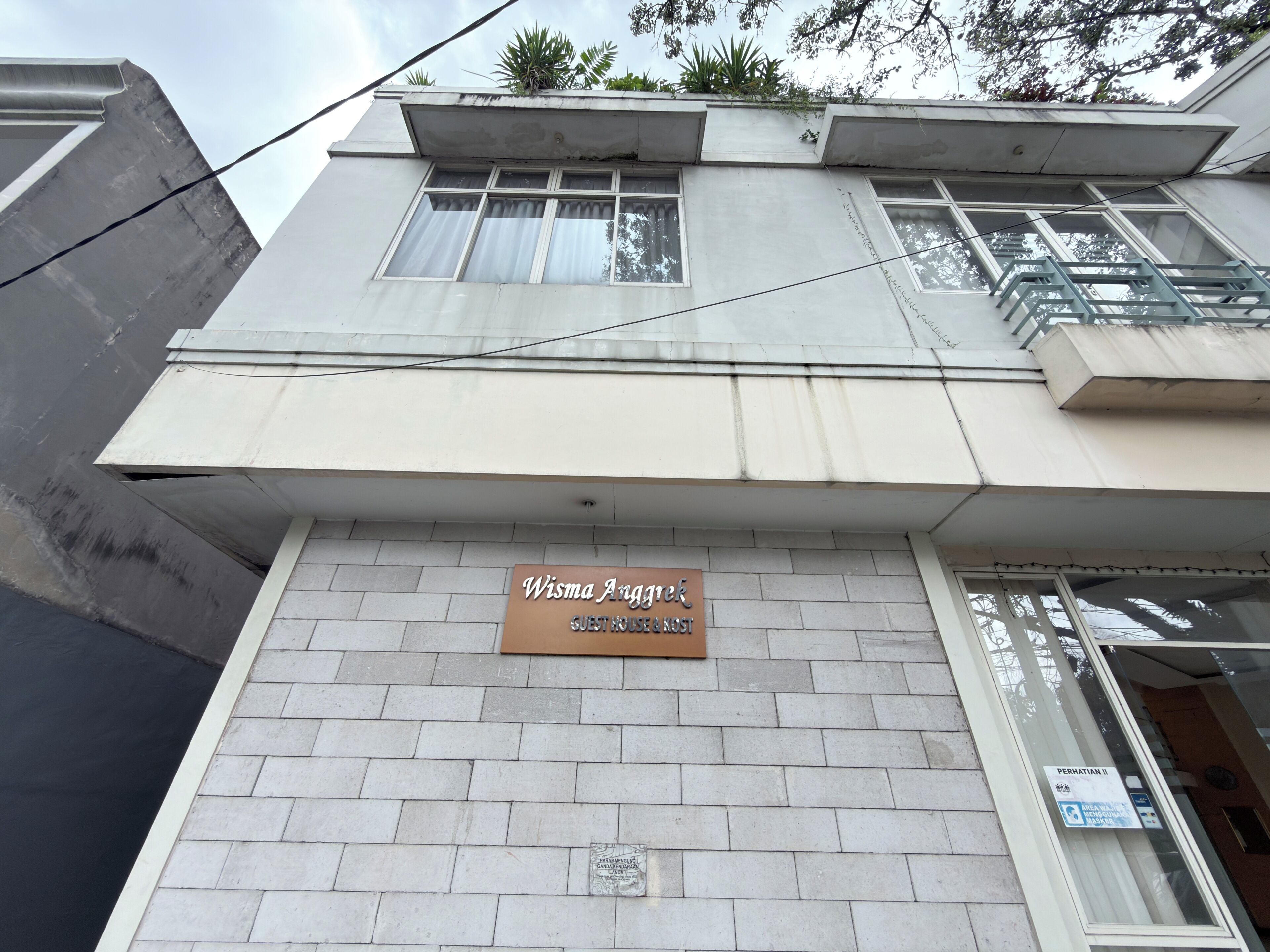 A building with a sign reading 'Wisma Angkrek Guesthouse & Rest.'