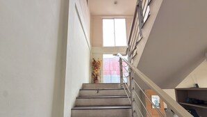 A staircase with metal railings, a potted plant, and a window at the top. - Guesthouse Anggrek BSD (South Tangerang)