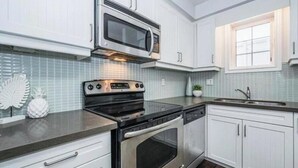 A kitchen with white cabinets, a microwave, an oven, and a sink. - 1 bed 1 bath Townhome (Kitchener)