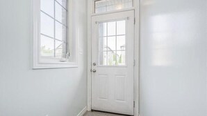 A white door with a window above it, a carpeted floor, and a white wall. - 1 bed 1 bath Townhome (Kitchener)