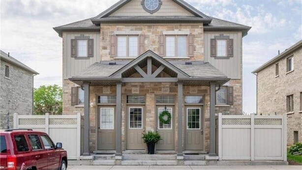 A two-story house with a symmetrical facade, a central entrance with a porch, and a small circular window above the door. - 1 bed 1 bath Townhome (Kitchener)