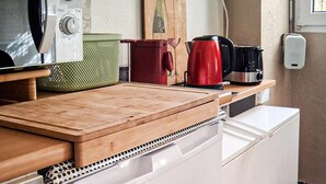 Une cuisine équipée d’une planche à découper en bois, d’une bouilloire, d’une machine à café et d’un four à micro-ondes.