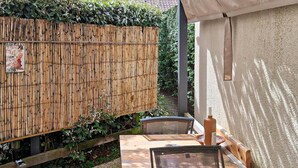 Une clôture en bois, une table avec des chaises et un mur avec une petite fenêtre.