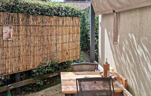 Une clôture en bois, une table avec des chaises et un mur avec une petite fenêtre.
