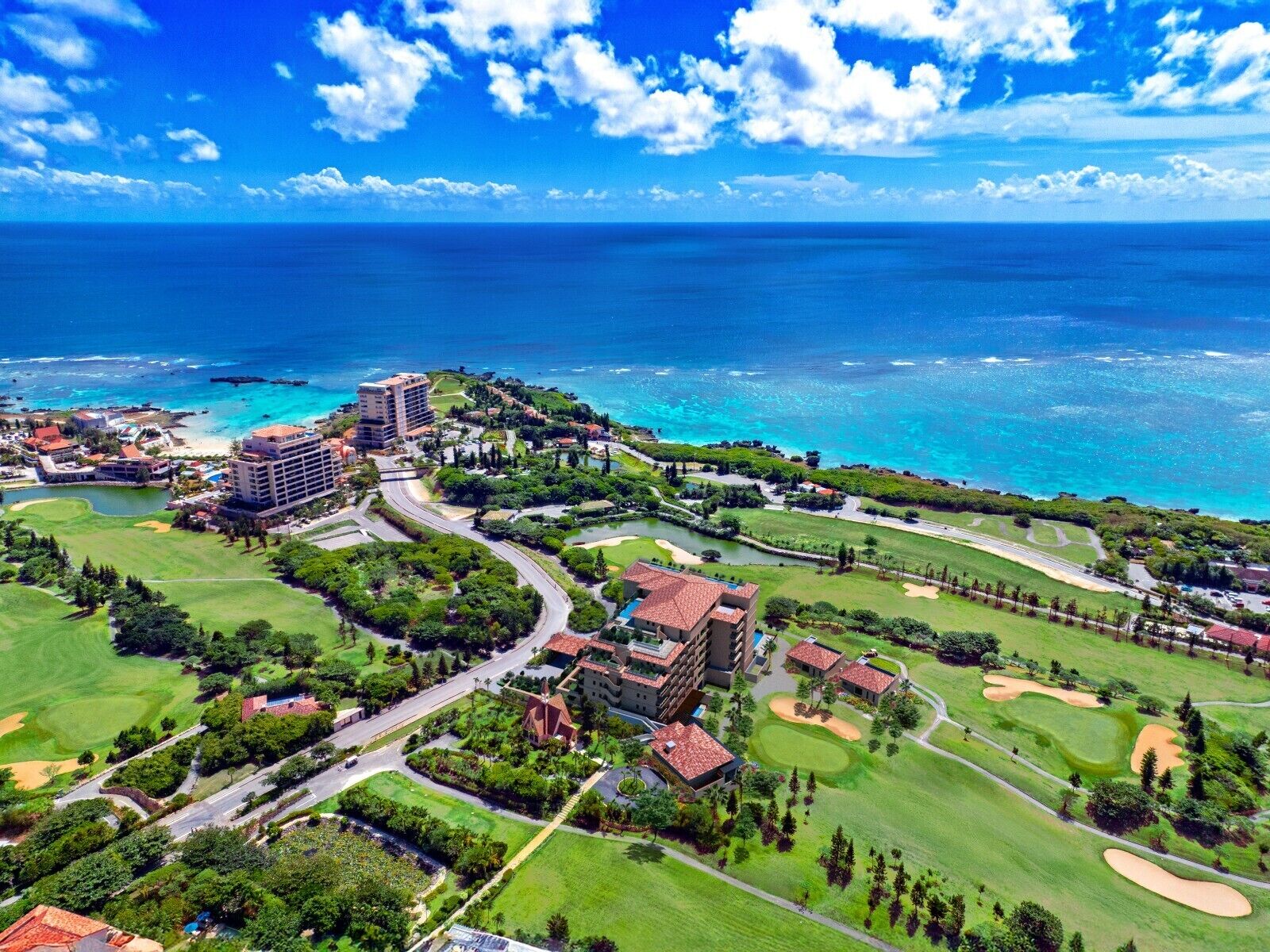 A resort with multiple buildings, golf courses, and a view of the ocean.