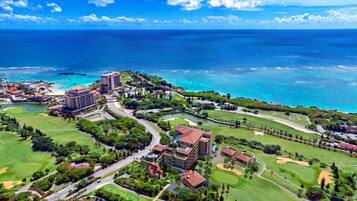 A resort with multiple buildings, golf courses, and a view of the ocean.