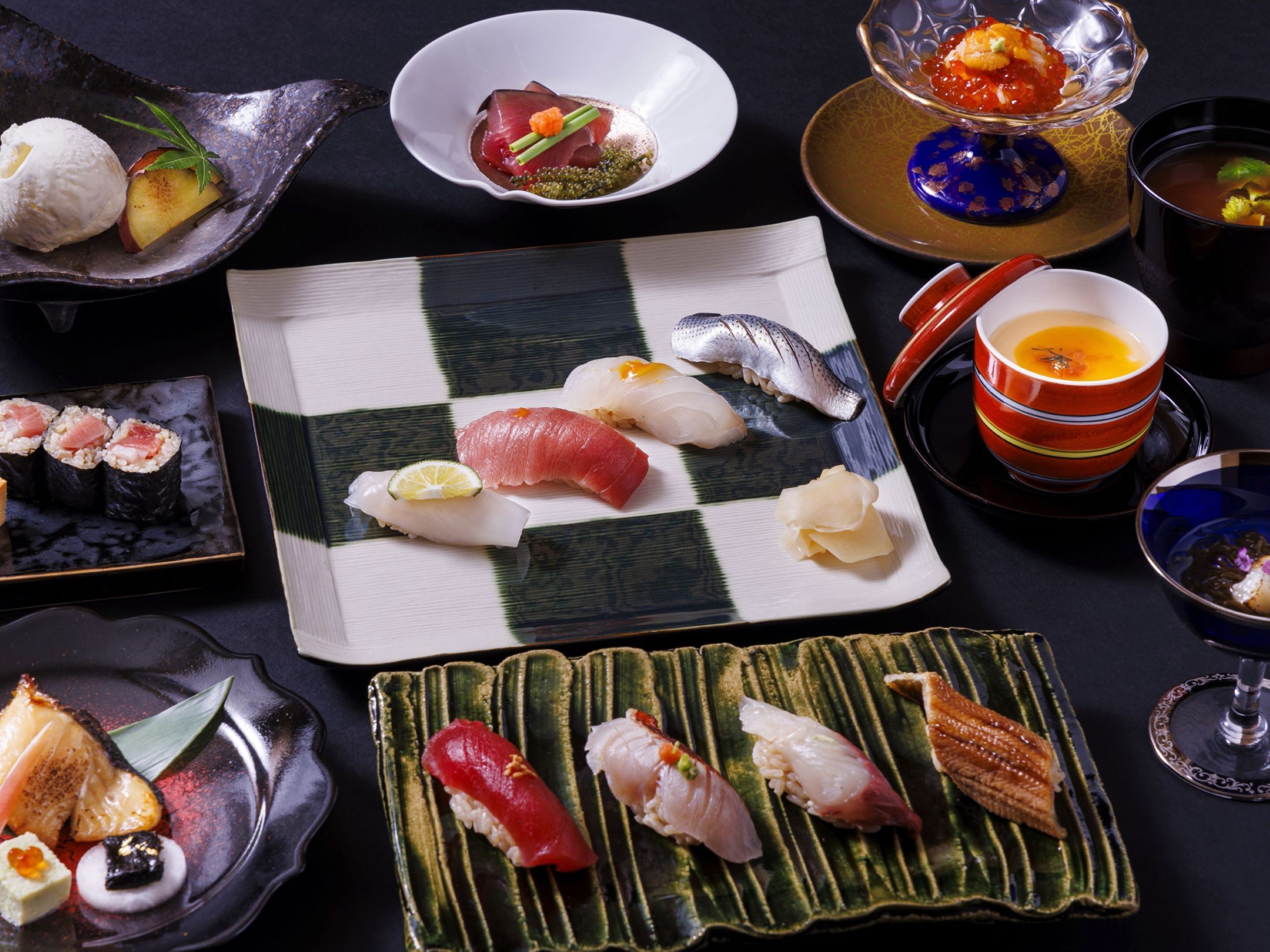 Variedad de platos de sushi en diferentes fuentes y recipientes.