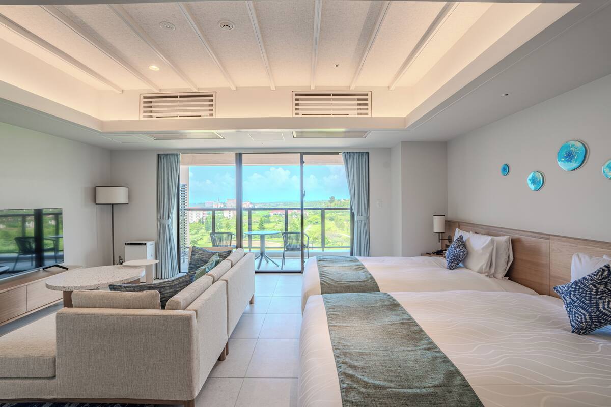 Une chambre d’hôtel avec un grand lit, un canapé, une table à manger et un balcon avec vue.
