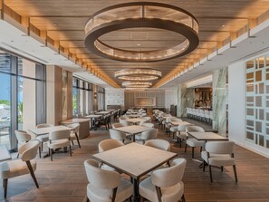 Un restaurante moderno con una barra alargada, techo alto y ventanas amplias.