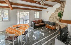 A room with a dining table, a sofa, a fireplace, and a view through the windows. - Awesome home in Le Plan-De-La-Tour (Le Plan-De-La-Tour)
