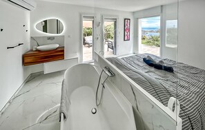 A modern bathroom with a bathtub, a vanity with a mirror, and a view of the outdoors. - 3 bedroom beautiful home in Roquebrune-sur-Argens (Roquebrune-sur-Argens)
