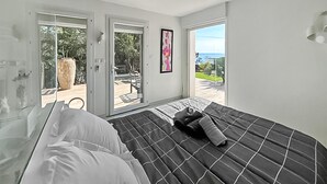 Een slaapkamer met een bed, een deur naar een buitenruimte en een raam met uitzicht.