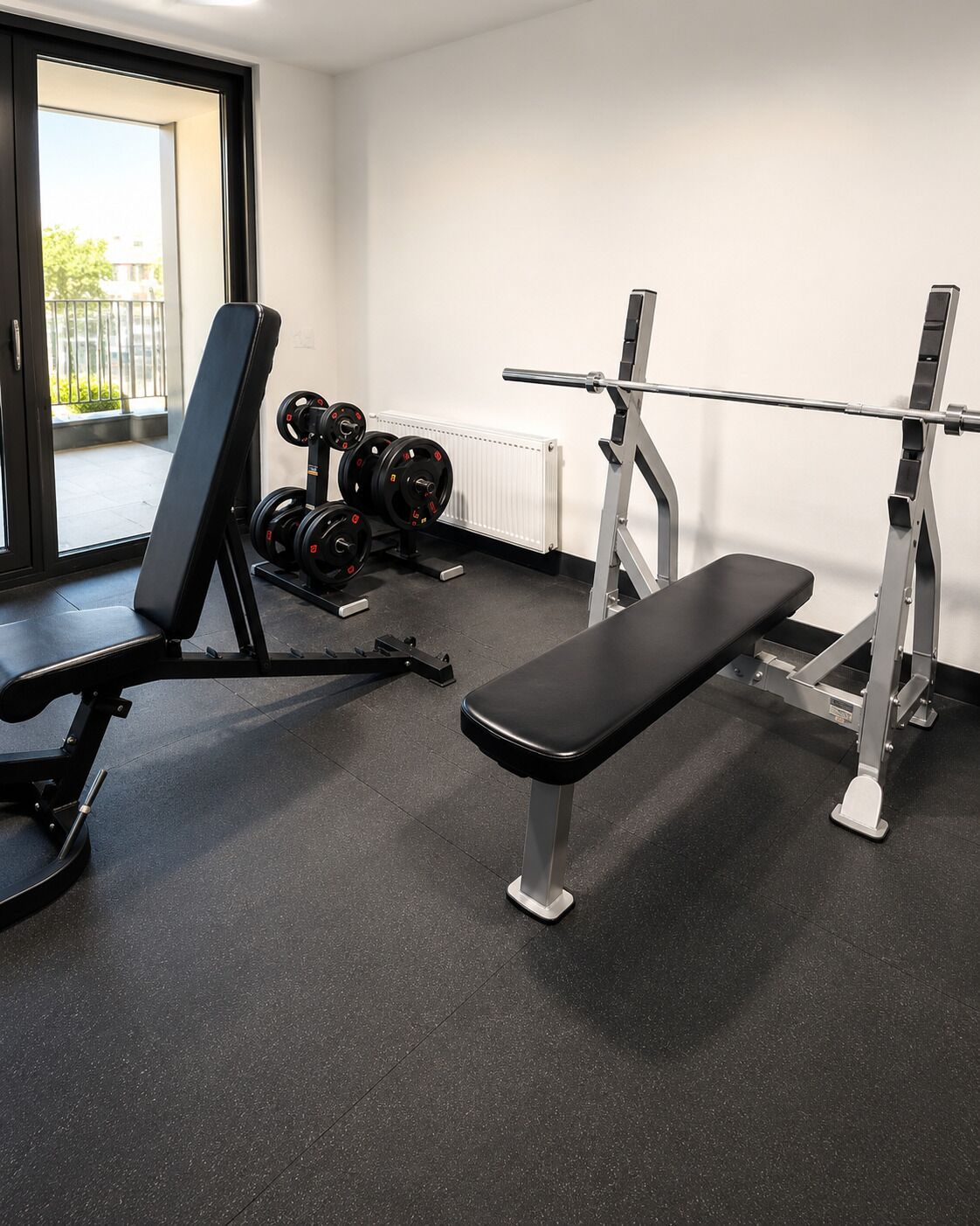 Een sportschool met een bank, gewichten en een squat rek.